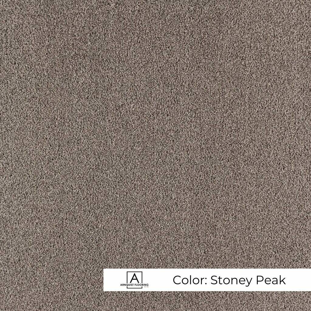 A close-up image of a textured carpet swatch in a neutral, earthy tone named "Highland Stoney Peak.