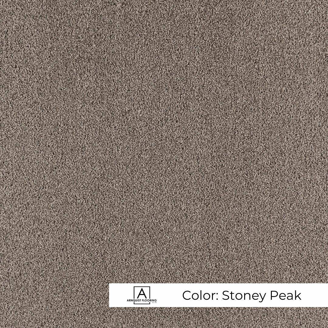 A close-up image of a textured carpet swatch in a neutral, earthy tone named 