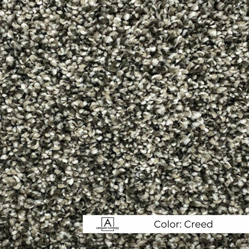 Close-up of a textured carpet in a blend of gray tones, labeled with the color "New Beginnings.