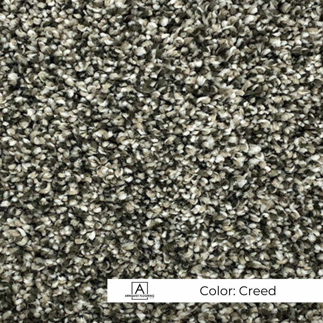 Close-up of a textured carpet in a blend of gray tones, labeled with the color 
